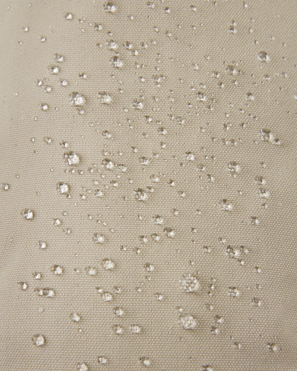 Macro close-up showing water perfectly beading off the earthy beige waterproof Reimatec exterior of the Reima Ote kids' winter mittens, demonstrating advanced rain and snow resistance.