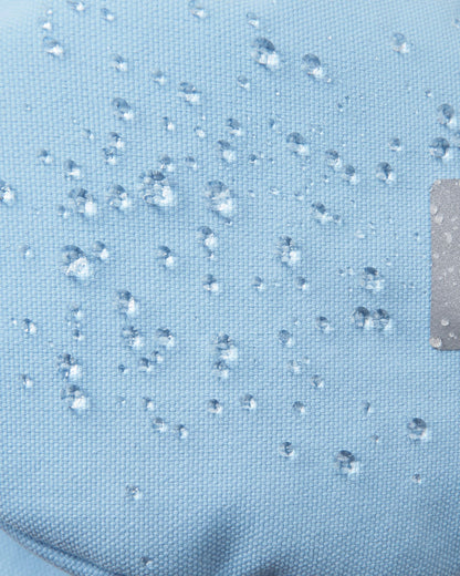 Macro close-up of water droplets beading tightly on the frozen blue Reimatec fabric of the Reima Ote kids' winter mittens, demonstrating extreme waterproof and weather-resistant performance for heavy snow play.