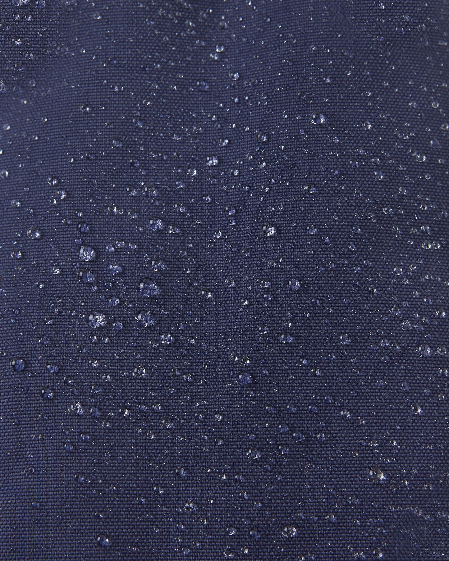 Macro close-up showing water perfectly beading off the navy blue waterproof Reimatec exterior of the Reima Ote kids' winter mittens, highlighting their advanced rain and snow resistance.