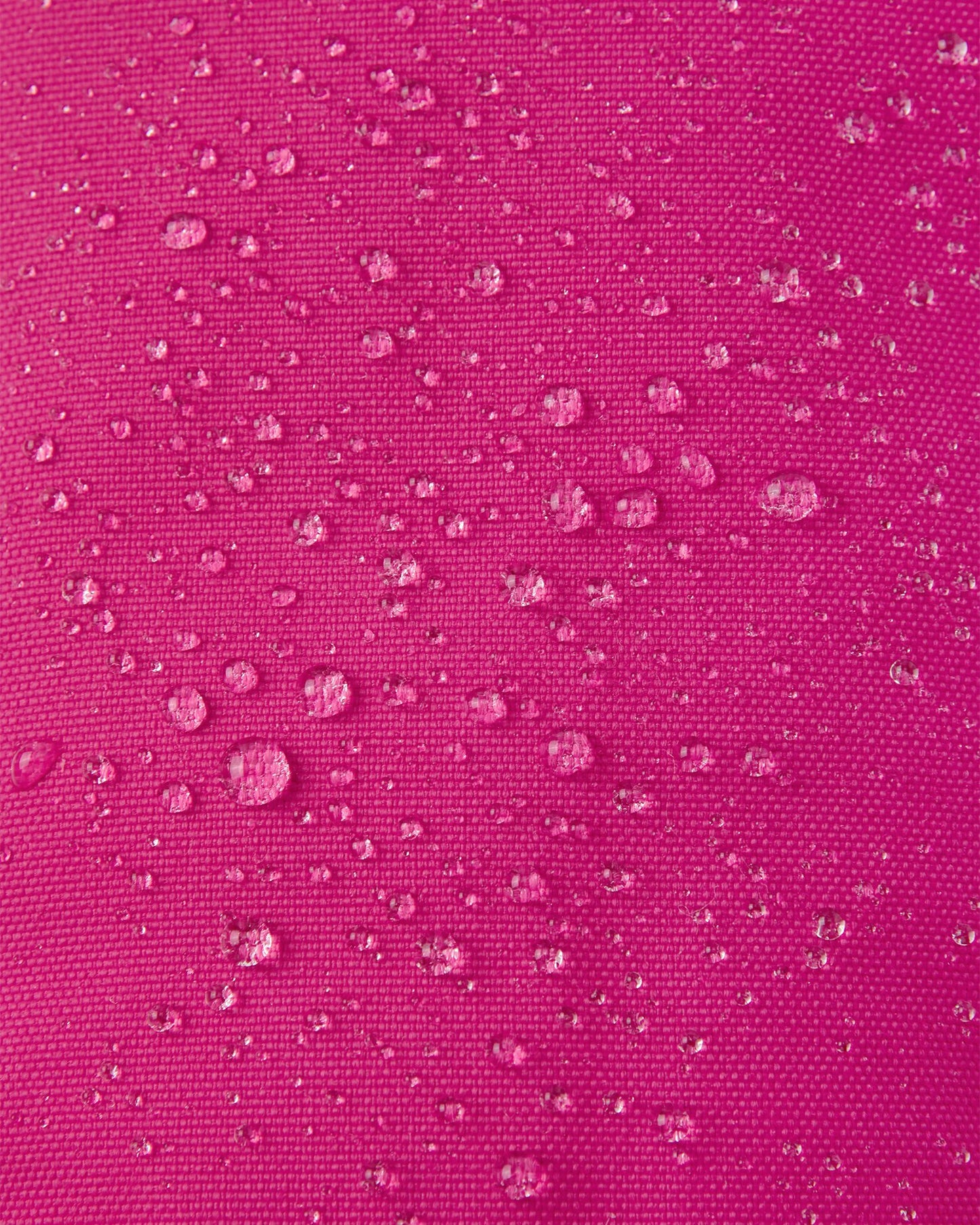 Macro close-up showing water droplets perfectly beading off the vibrant rosy berry Reimatec waterproof fabric of the Reima Ote kids' winter mittens.