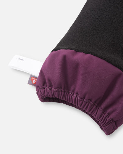 Close-up of the inner cuff on the deep purple Reima Ote kids' winter mittens, displaying the cozy black fleece lining, an inner name tag, and a PrimaLoft insulation label indicating high-performance heat retention.