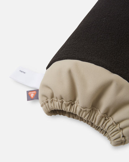 Inside cuff view of the earthy beige Reima Ote kids' winter mittens, highlighting the warm black fleece lining, an inner name tag, and a PrimaLoft insulation label for superior thermal heat retention.
