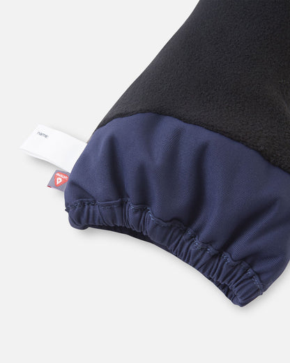 Close-up of the inner cuff on the navy blue Reima Ote kids' winter mittens, displaying the cozy black fleece lining, an inner name tag, and a PrimaLoft insulation label indicating high-performance thermal heat retention.