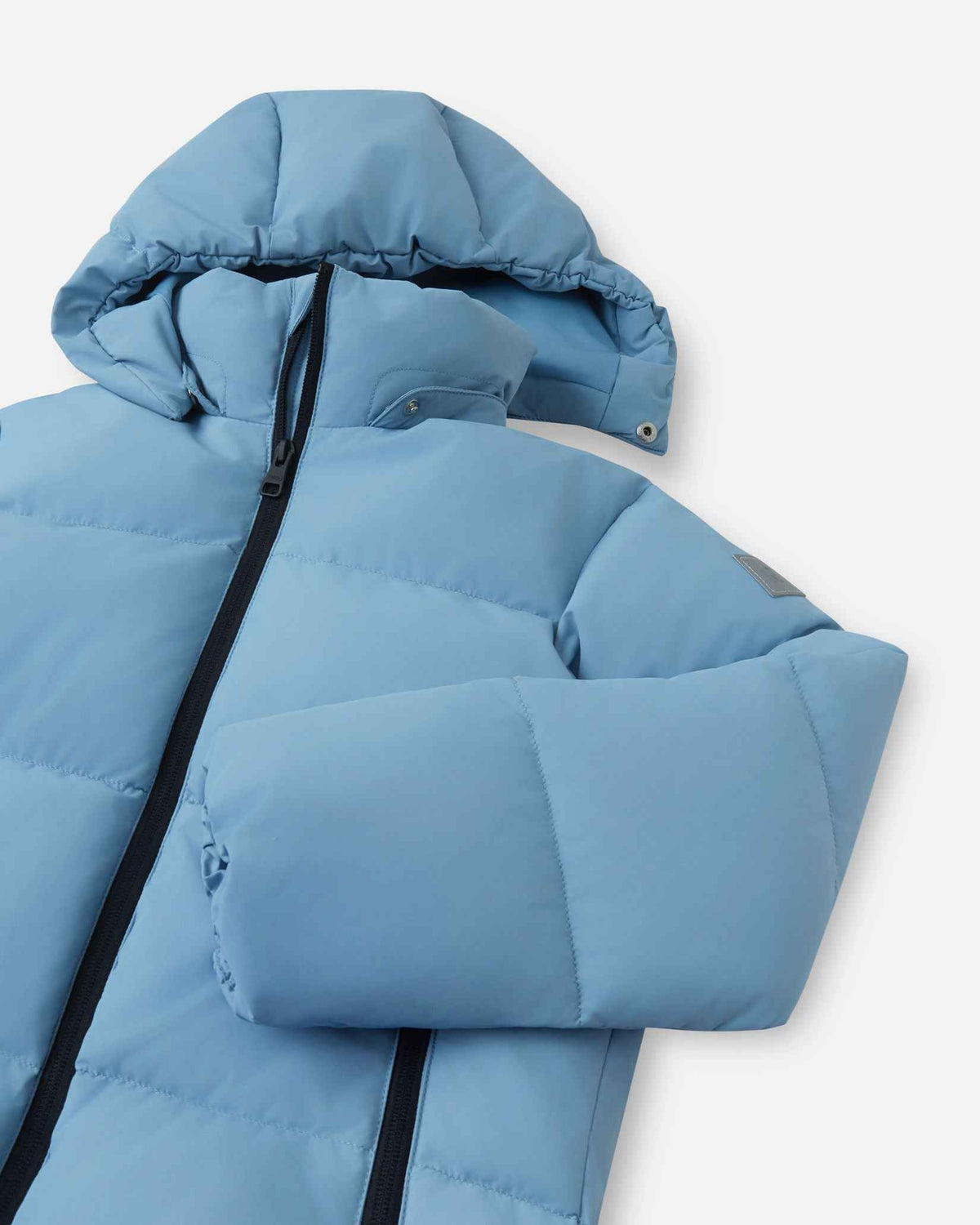 Close-up angled view of the upper torso, stand collar, and snap-off insulated hood on the cloudy blue Reima Paimio kids' winter down jacket, designed for versatile cold-weather protection.