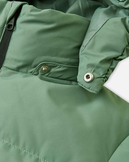Detailed close-up of the disconnected metallic snap fastener on the collar of the green clay Reima Paimio kids' winter down jacket, demonstrating the safe, tear-away removable hood mechanism designed to easily release if snagged during active outdoor play.
