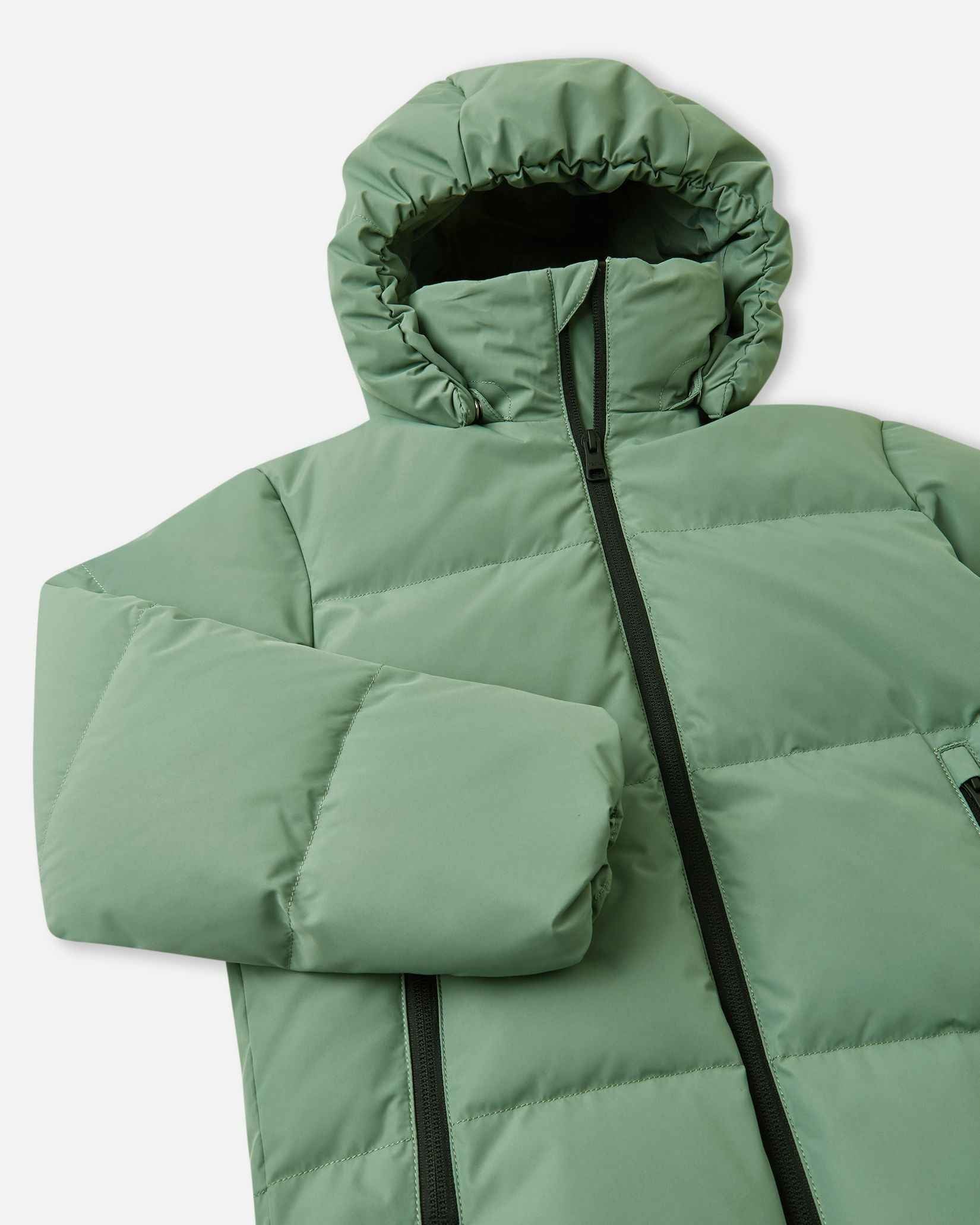 Close-up of the upper chest and stand collar on the green clay Reima Paimio kids' snow jacket, focusing on the chin guard, sturdy zipper, and child-safe detachable hood snaps.