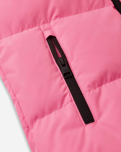 Close-up detail of the vertical side hand pocket on the soft coral Reima Paimio kids' winter coat, featuring a secure black zipper to keep small hands warm and essentials safe on the slopes.