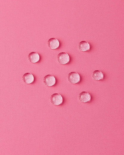 Macro close-up of water droplets forming beads on the soft coral pink outer shell of the Reima Paimio jacket, illustrating the highly water-resistant, dirt-repellent, and breathable material.