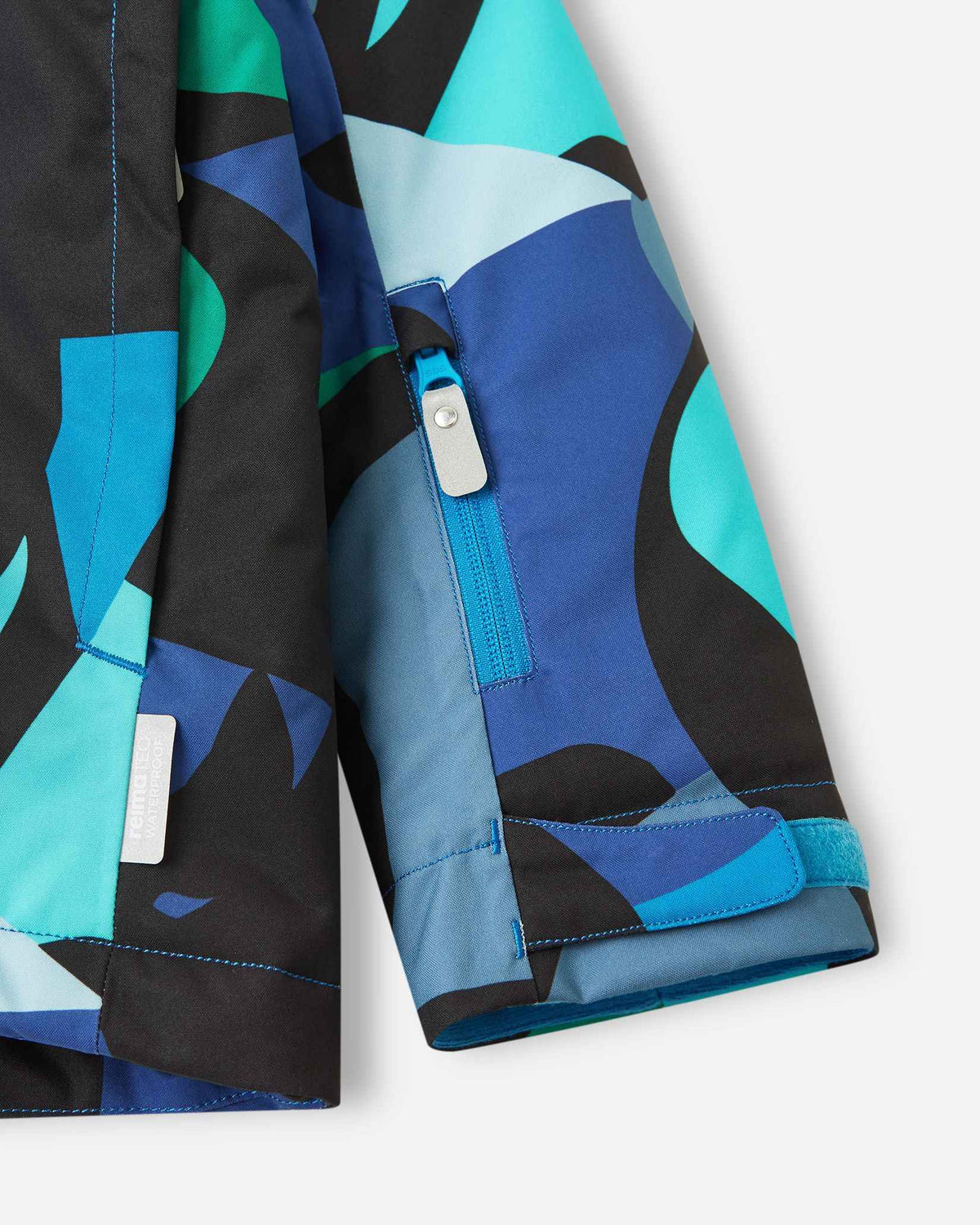 A close-up of the cuff on a kids' ski jacket, showing off the cool aquatic pattern of abstract blue, black, and teal shapes.