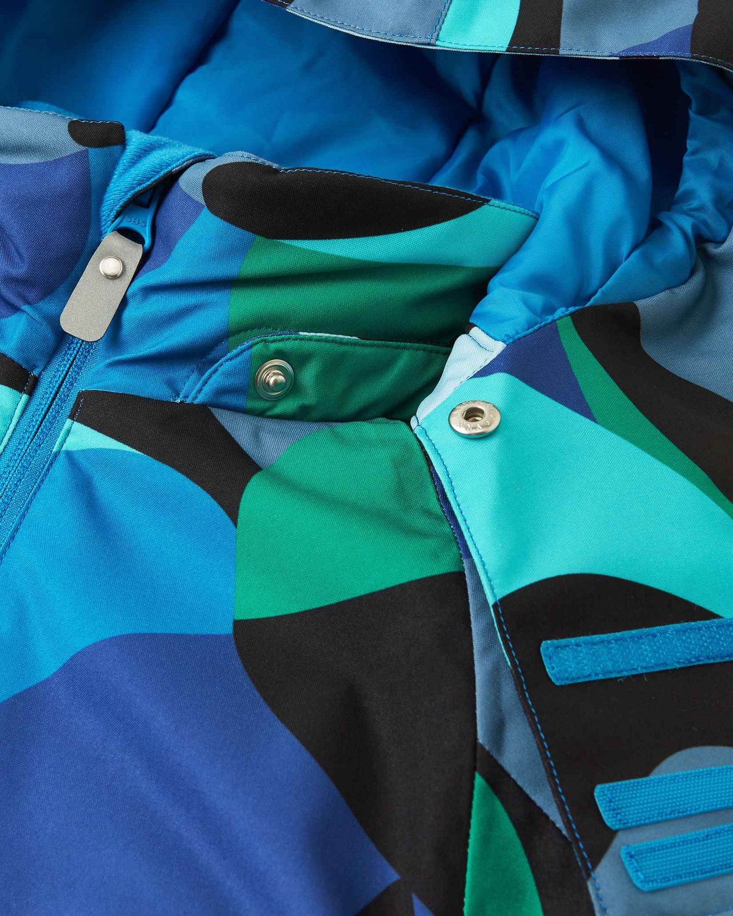 Close-up fabric detail showing the colorful geometric aquatic pattern on the Reima Palsi Ski Jacket.