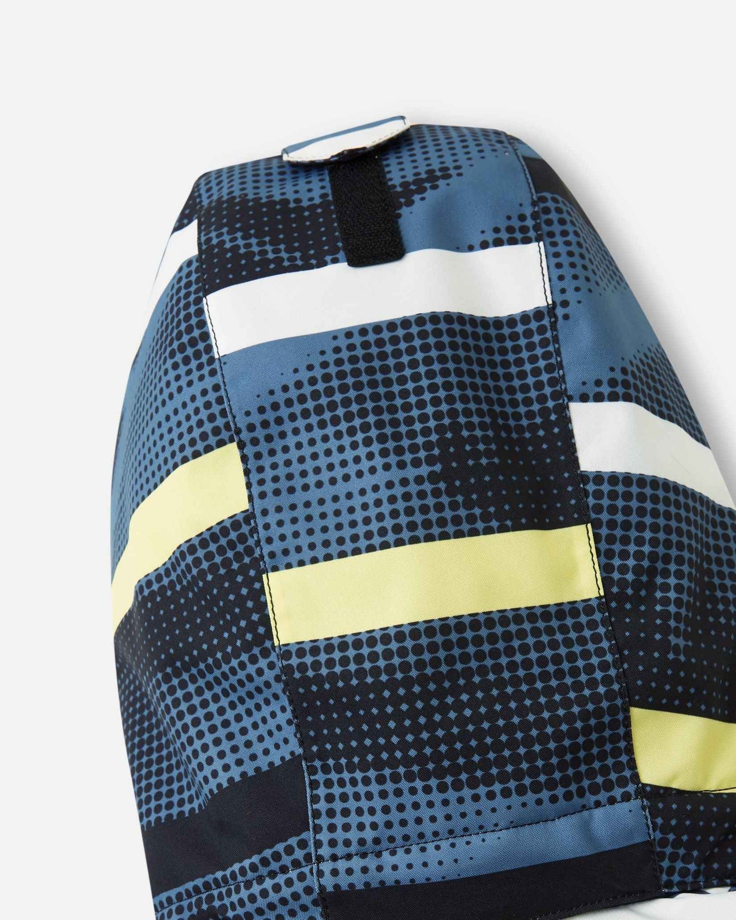 A close view of the hood attachment area on the Blue Ocean Reima Palsi ski jacket featuring a dark blue dotted pattern with yellow and white stripes.