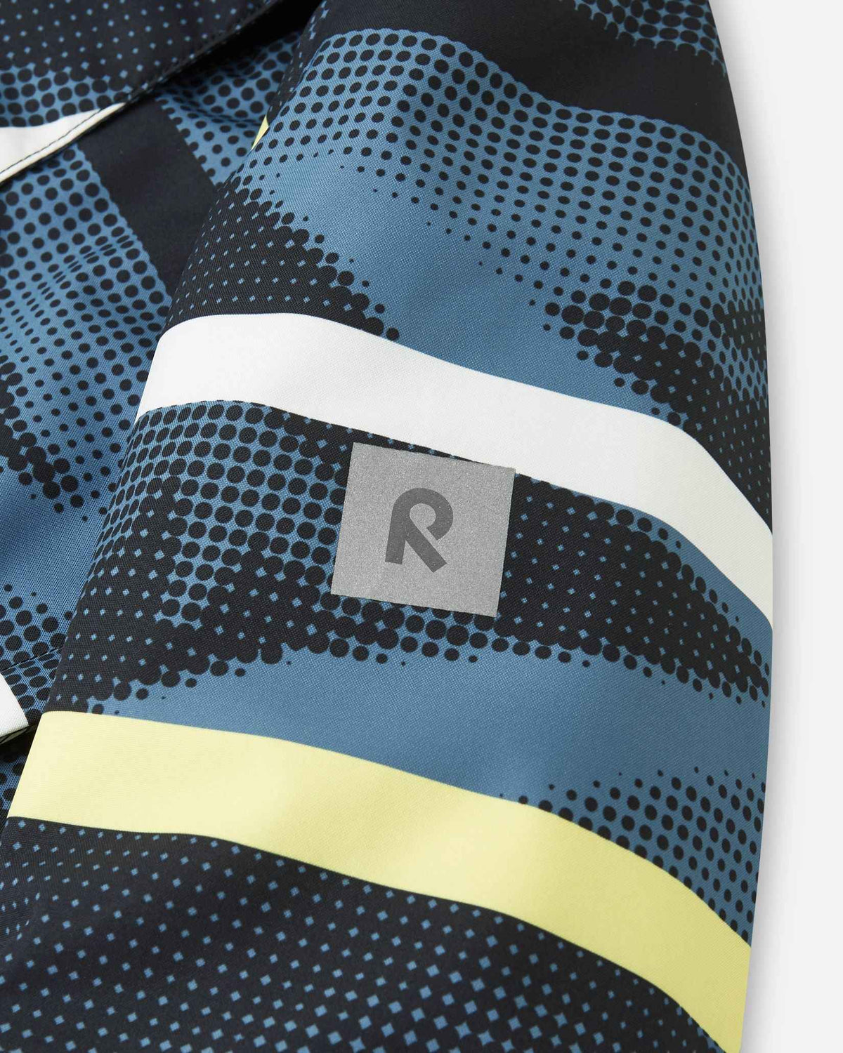 The sleeve of the dark ocean blue jacket features a small reflective Reima logo patch.