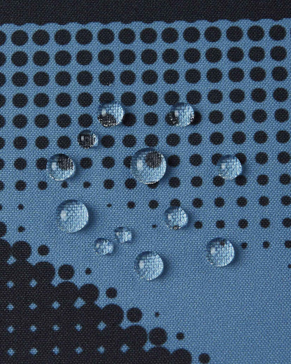 Close-up of water droplets resting on the Blue Ocean patterned fabric of the Reima Palsi Ski Jacket, highlighting its waterproof material.