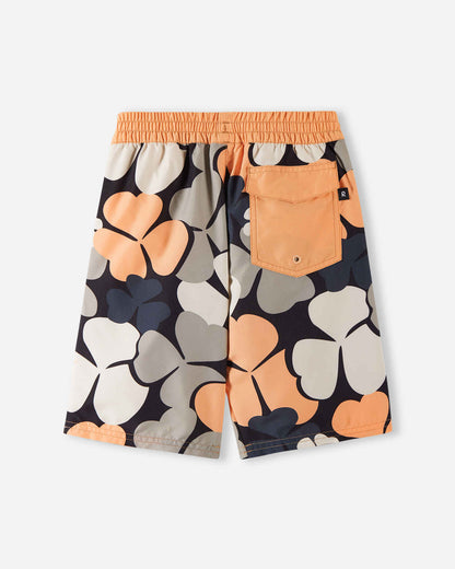 Back view of the apricot Reima Papaija boys' UPF 50+ board shorts, highlighting a solid apricot flap pocket on the back with a water drainage eyelet, set against a bold floral pattern.