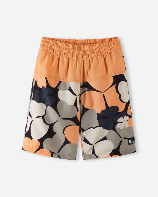 Front view of the Reima Papaija boys' UPF 50+ sunproof swim shorts, featuring a solid apricot orange waistband over a stylish oversized floral clover print in apricot, beige, and black.