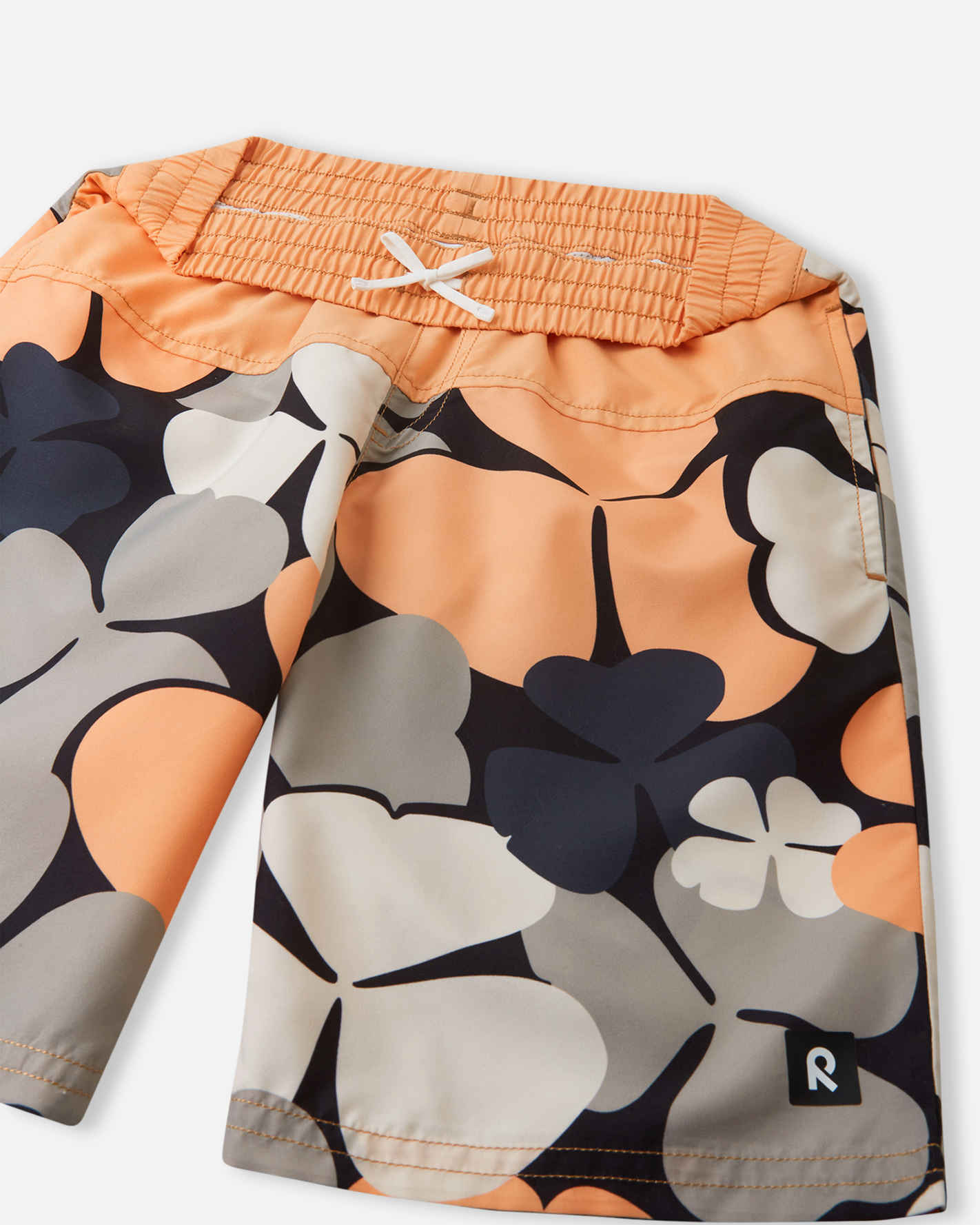 Detailed close-up of the Reima Papaija boys' apricot swim shorts, focusing on the gathered elastic waistband and the sturdy white inner drawstring designed to keep shorts secure during water play.
