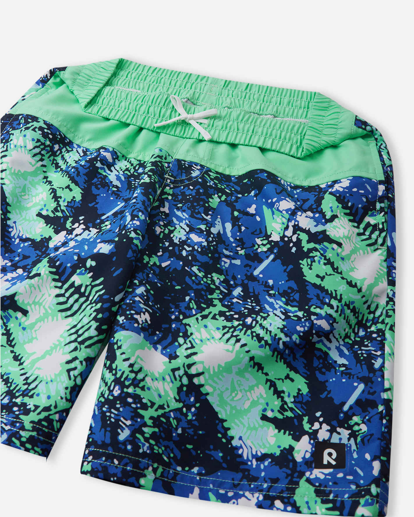 Close-up detail of the Reima Papaija boys' fresh mint swim shorts, highlighting the comfortable gathered elastic waistband with a secure adjustable white inner drawstring for a custom fit.