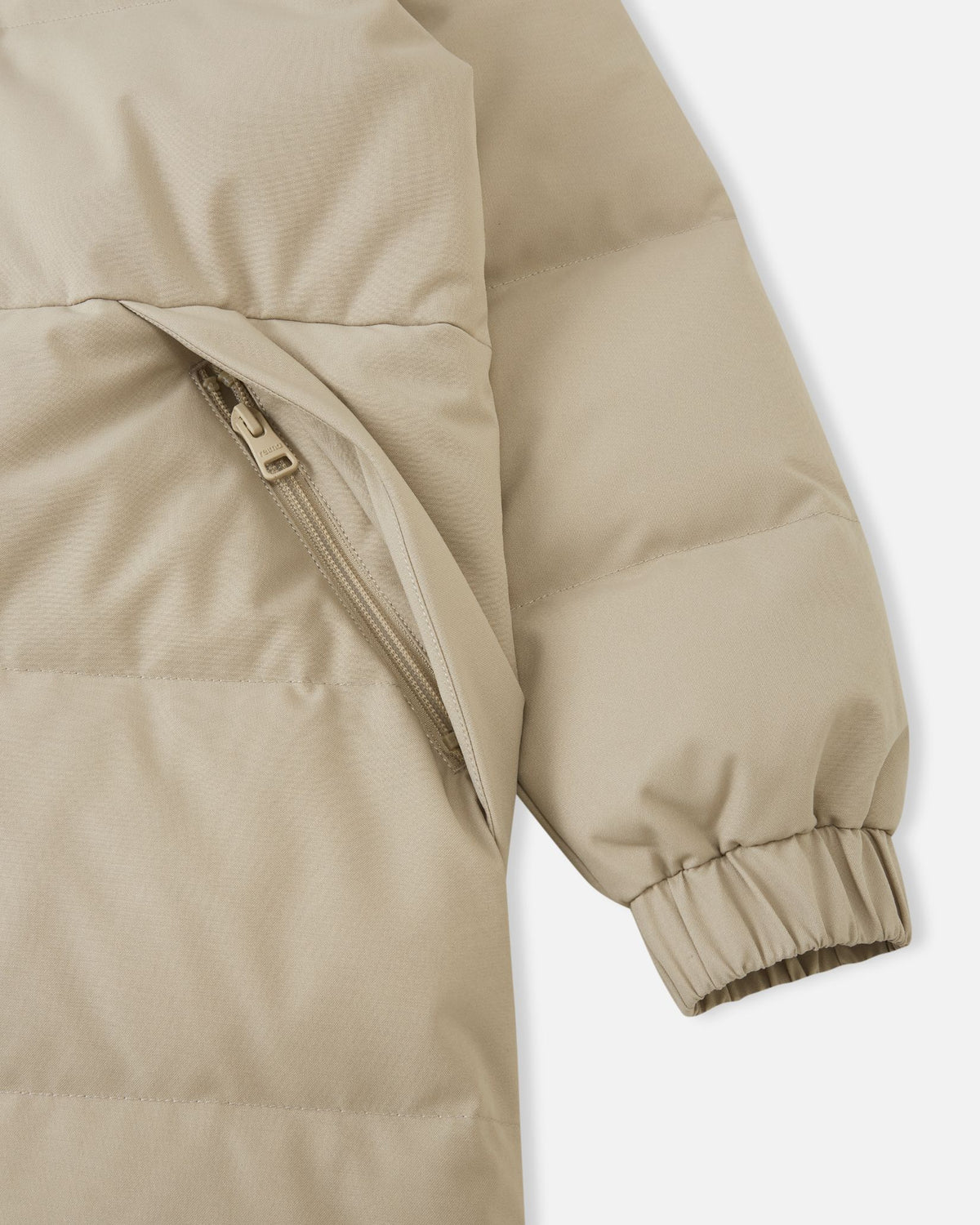 Macro detailed shot of the lower section of the Reima Parkkala girls' long down winter coat, displaying the ribbed elastic knit cuff construction and the entry of a large patch pocket, emphasizing comfort and storage.