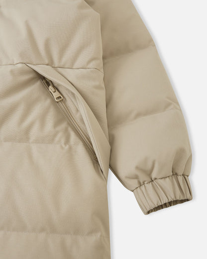 Macro detailed shot of the lower section of the Reima Parkkala girls' long down winter coat, displaying the ribbed elastic knit cuff construction and the entry of a large patch pocket, emphasizing comfort and storage.