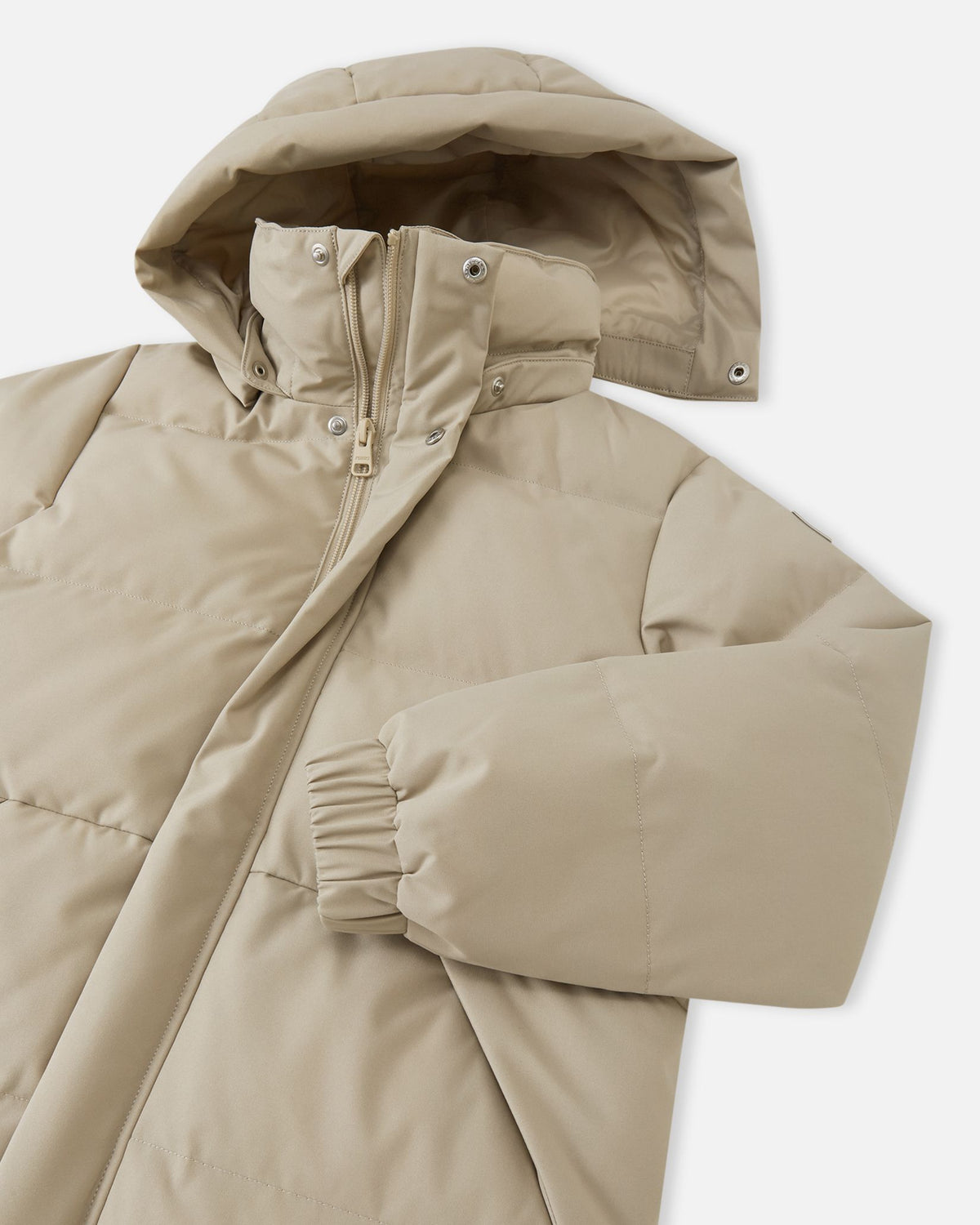 Detailed close-up image showcasing the upper section of the Reima Parkkala girls' long down winter coat in Earthy Beige, focusing on the insulated hood, the protective collar, and the full-length front zipper system with snapping wind flap.