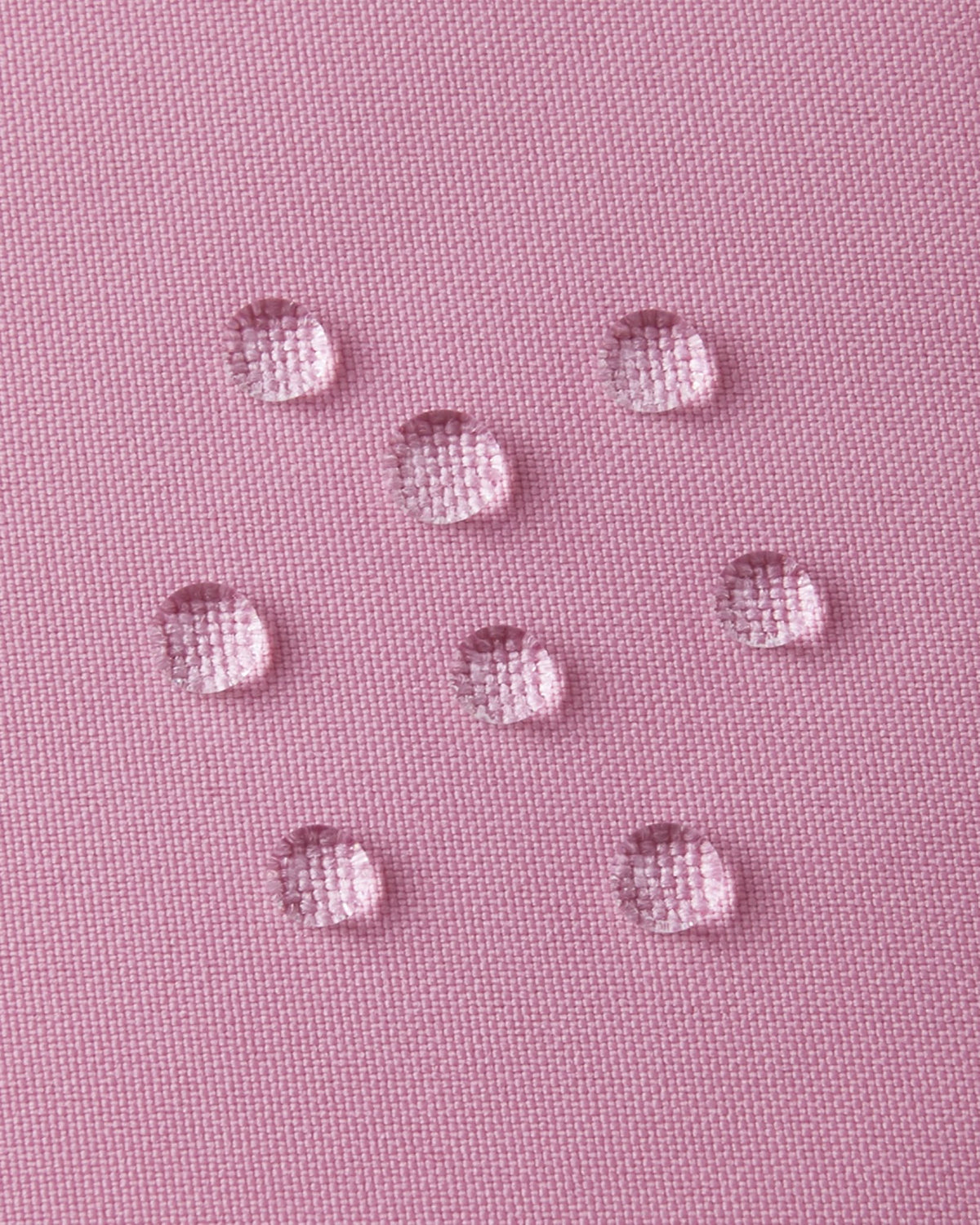 Extreme macro shot of water droplets forming tight beads on the grey pink outer fabric of the Reima Parkkala long down coat, demonstrating its premium BIONIC-FINISH ECO dirt- and water-repellent surface.