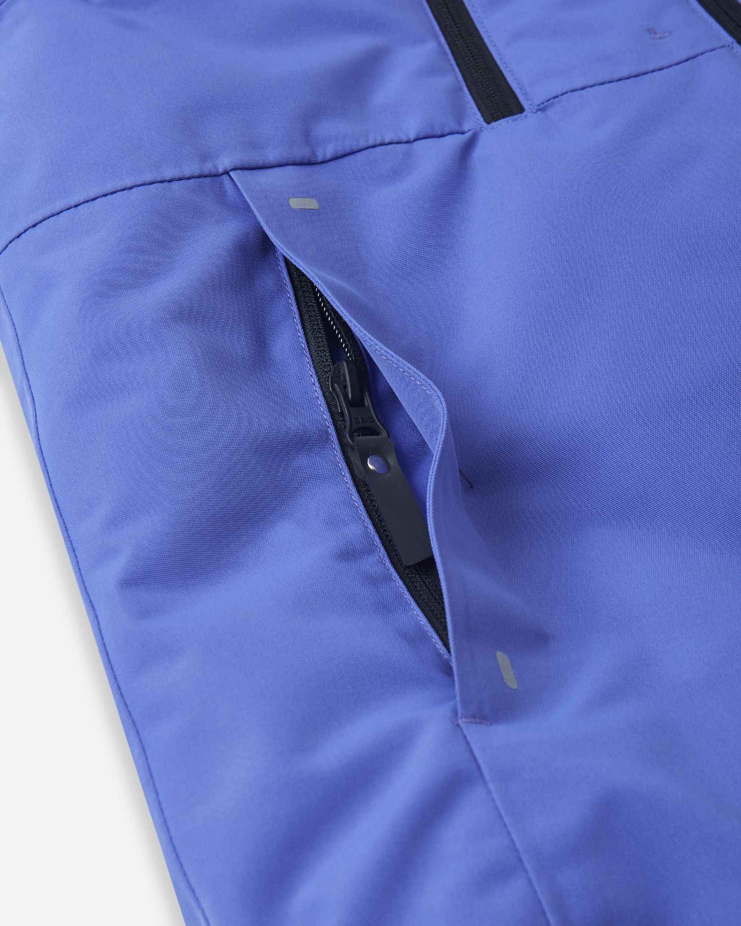 Detail shot of the securely zippered side hand pocket on the breezy violet Reima Perille kids' ski coat, designed to safely store small essentials and keep hands warm.