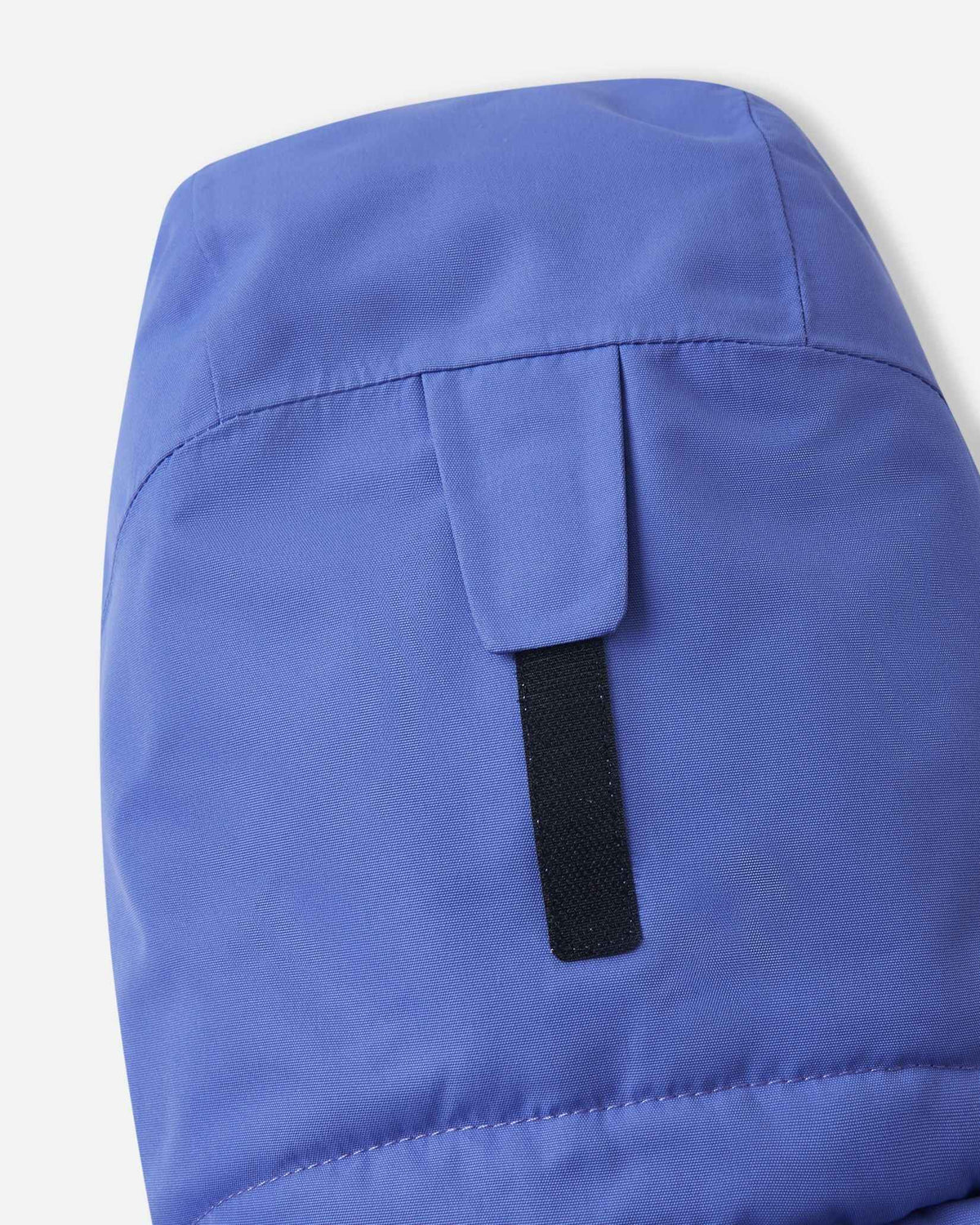 Close-up of the back of the hood on the breezy violet Reima Perille ski jacket, featuring a sturdy hook-and-loop tab for easy volume adjustment over a ski helmet.