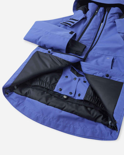 Open interior view of the lower hem on the breezy violet Reima Perille kids' snow jacket, revealing the integrated powder skirt (snow lock) snapped closed, featuring a secure jacket-to-pants connector and adjustable drawcord to completely block out loose powder.