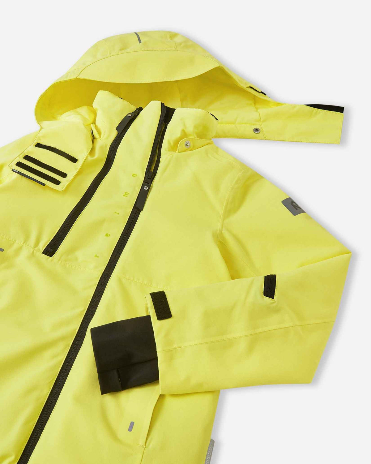 Close-up detail of the upper front on the yellow Reima Perille kids' ski jacket, showing the dual front zipper ventilation system, high wind-blocking collar, and adjustable hook-and-loop sleeve cuffs.