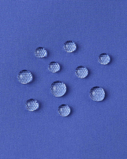 Macro photography of water droplets beading off the breezy violet outer shell of the Reima Perille ski jacket, demonstrating the high-performance BIONIC-FINISH ECO water and dirt repellent technology.