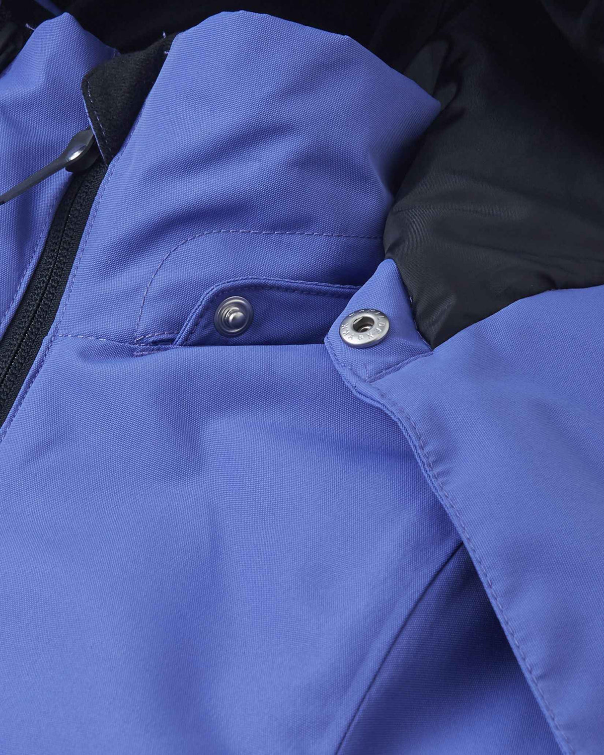 Detail view of the metallic snap fastener connecting the collar and hood of the breezy violet Reima Perille kids' jacket, showcasing the safe, easily detachable hood mechanism.