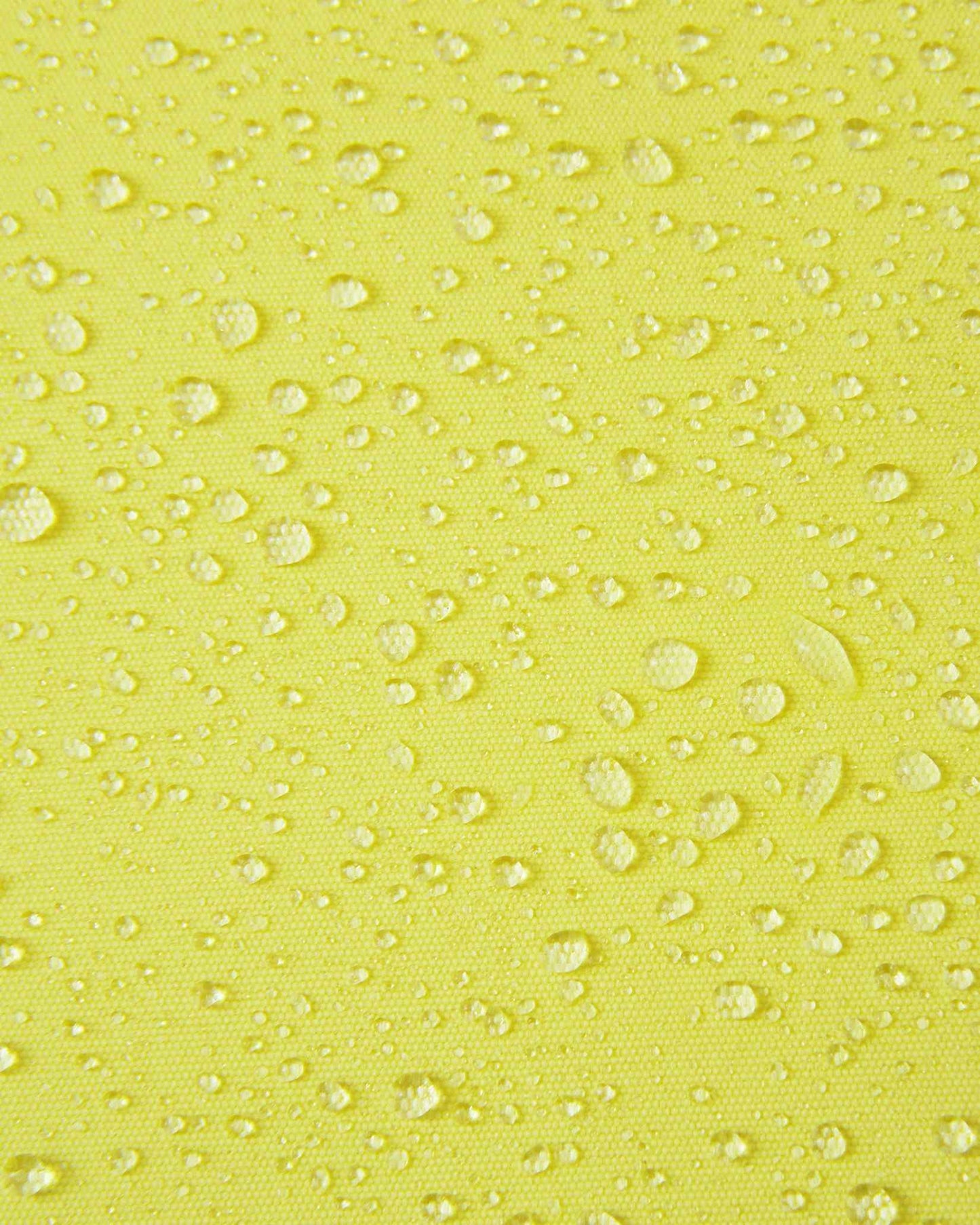 Macro close-up of water droplets beading and rolling off the bright yellow outer fabric of the Reima Perille ski jacket, illustrating the high-performance breathable, windproof, and waterproof Reimatec coating.