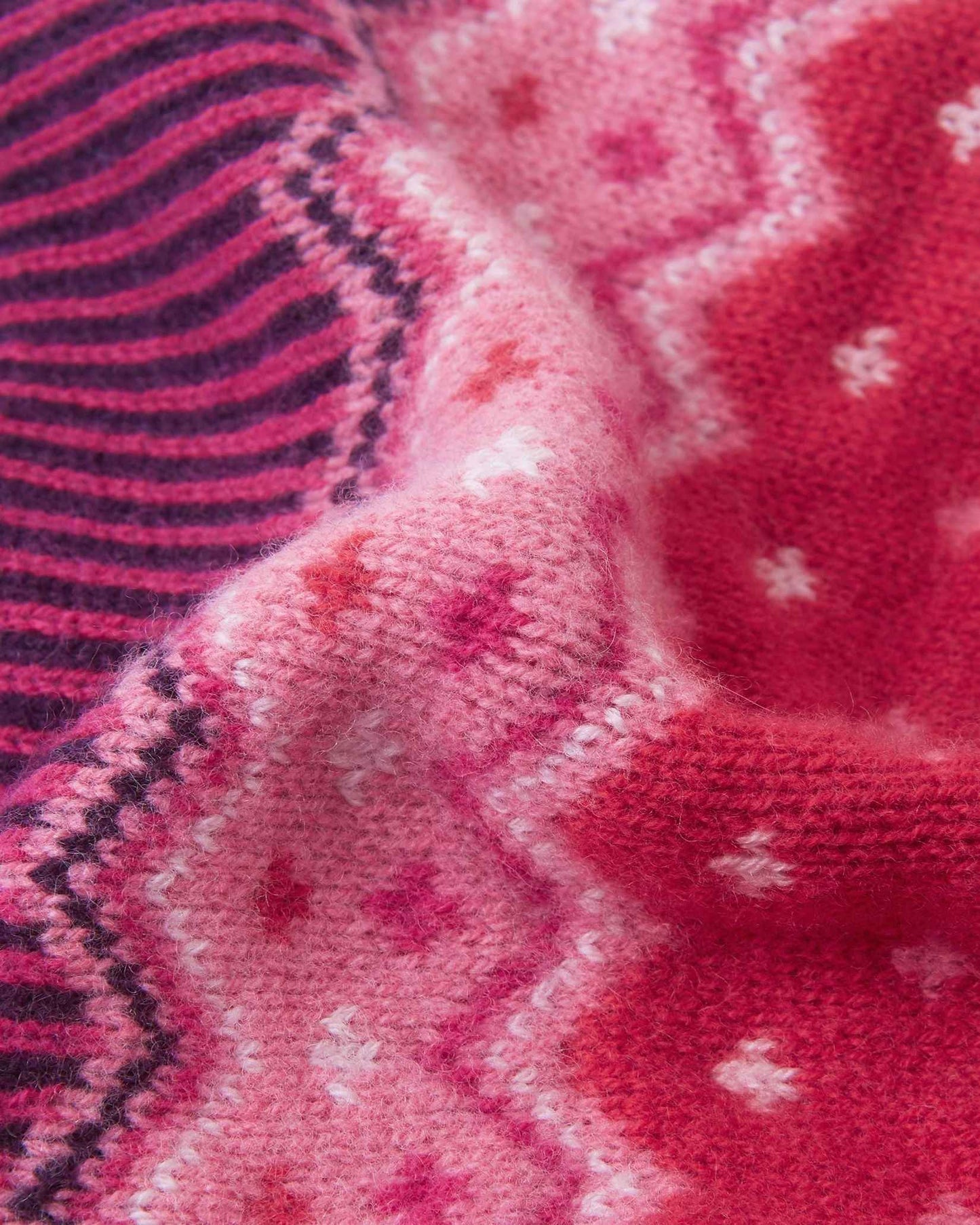 Macro close-up of the intricate jacquard knit texture on the deep purple Reima Pohjoinen kids' winter beanie, highlighting the soft, insulating merino wool yarn structure.