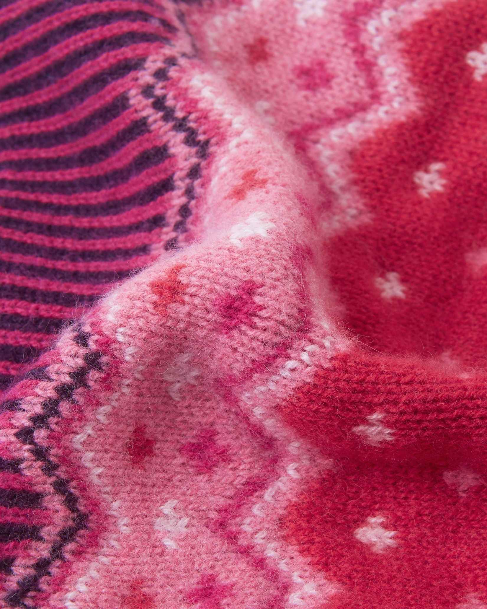 Macro close-up of the intricate jacquard knit texture on the deep purple Reima Pohjoinen kids' winter beanie, highlighting the soft, insulating merino wool yarn structure.