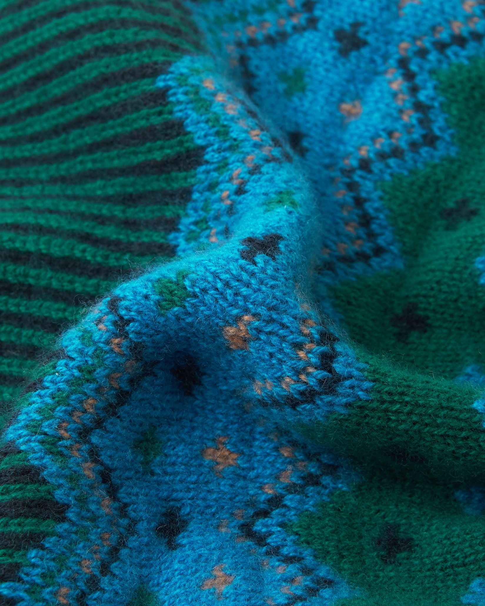 Macro close-up of the premium navy, green, and azure blue merino wool knit on the Reima Pohjoinen kids' beanie, demonstrating the soft yarn density and rich colorway.
