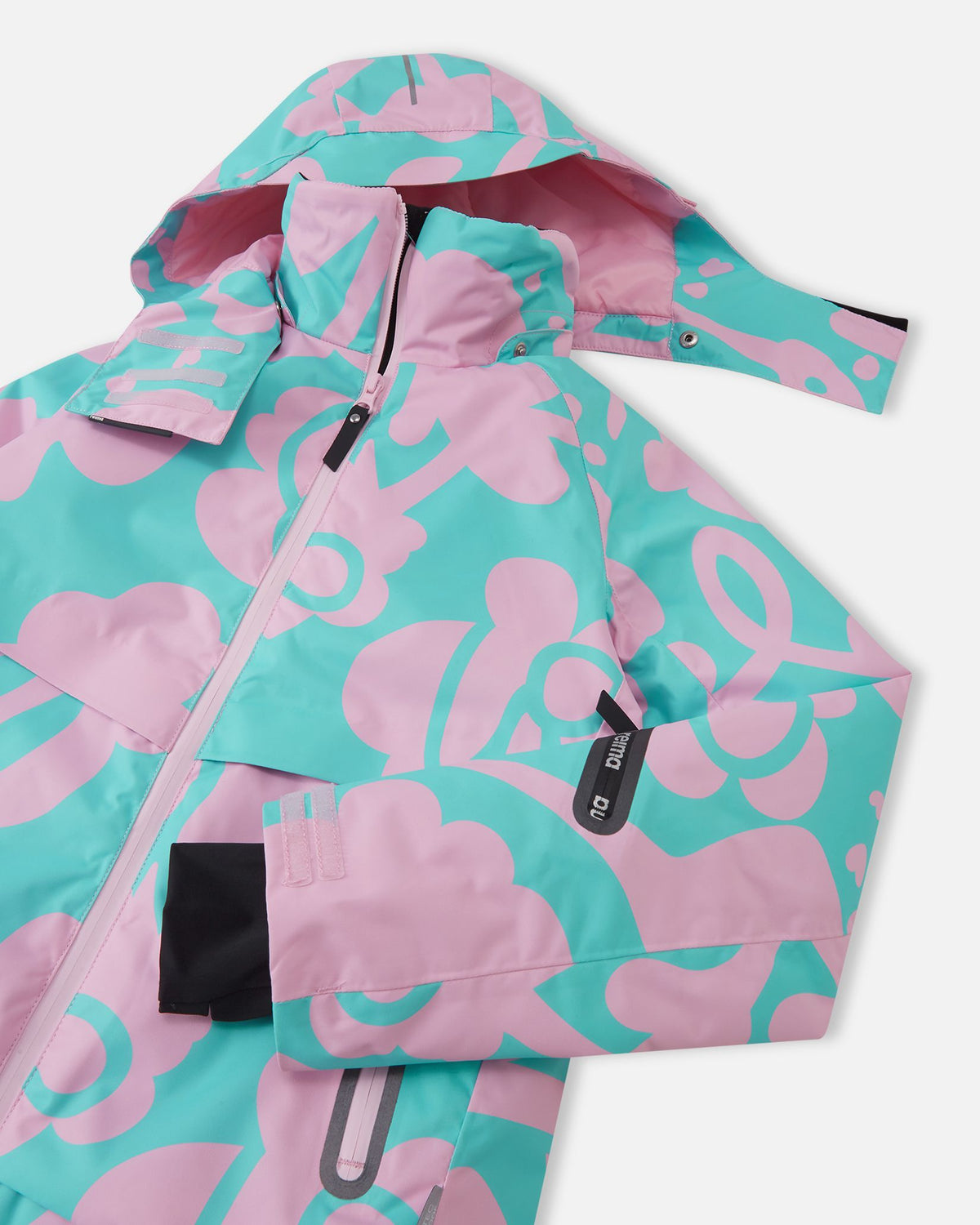 Close-up of the upper chest on the Reima Posio girls' ski jacket in light heather, detailing the snap buttons for the detachable hood, the protective front zipper wind flap, and the left sleeve ski pass pocket.