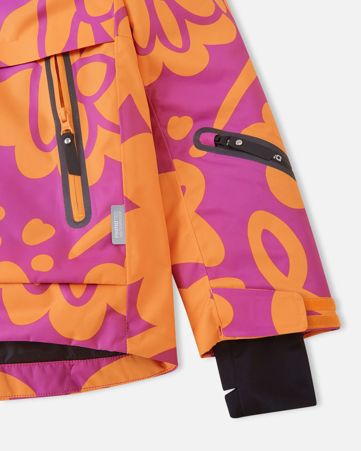 Close-up of the sleeve on the Reima Posio girls' ski jacket, showing the adjustable Velcro outer cuff, black Lycra inner cuff with thumbhole, water-repellent zipper on the ski pass pocket, and the Reimatec waterproof tag.