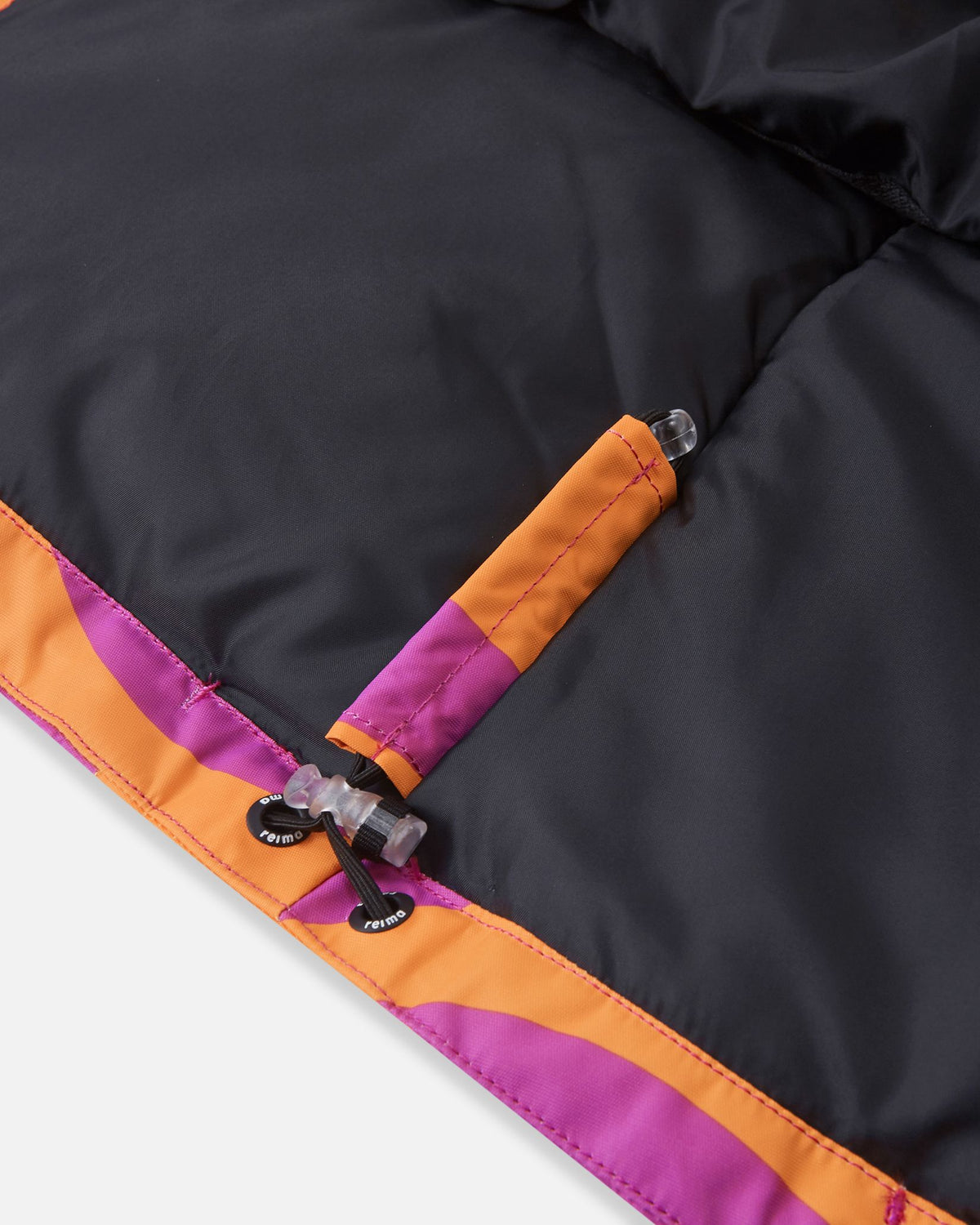 Close-up of the interior bottom hem on the Reima Posio girls' ski jacket, highlighting the elastic bungee cord and secure toggle lock designed to adjust the fit and block out cold winter drafts.
