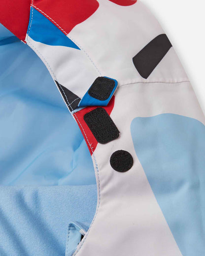 Detailed look at the secure velcro hood fasteners and protective neck baffle on the white floral Reima Posio kids' breathable ski jacket, ensuring a completely draft-free fit around the face.