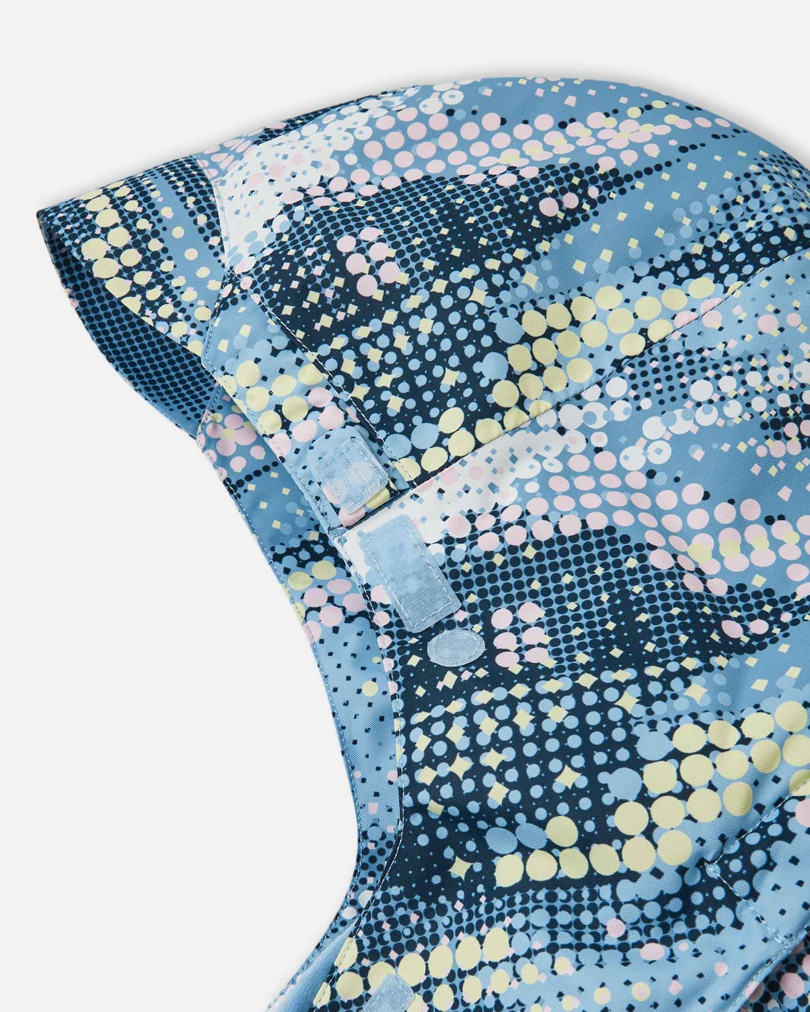 Close-up view of the adjustable velcro strap on the back of the helmet-compatible hood of the frozen blue Reima Posio kids' waterproof winter ski jacket.