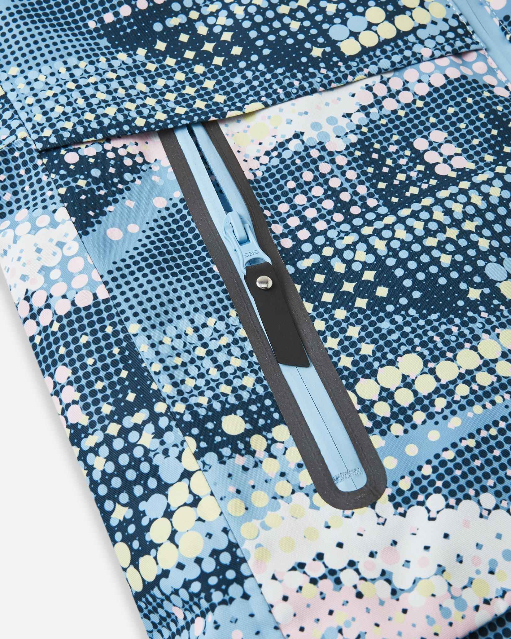 Close-up of the sealed, water-resistant zipper pocket on the front panel of the frozen blue Reima Posio kids' winter ski jacket, showcasing the durable construction designed for snow and rain.