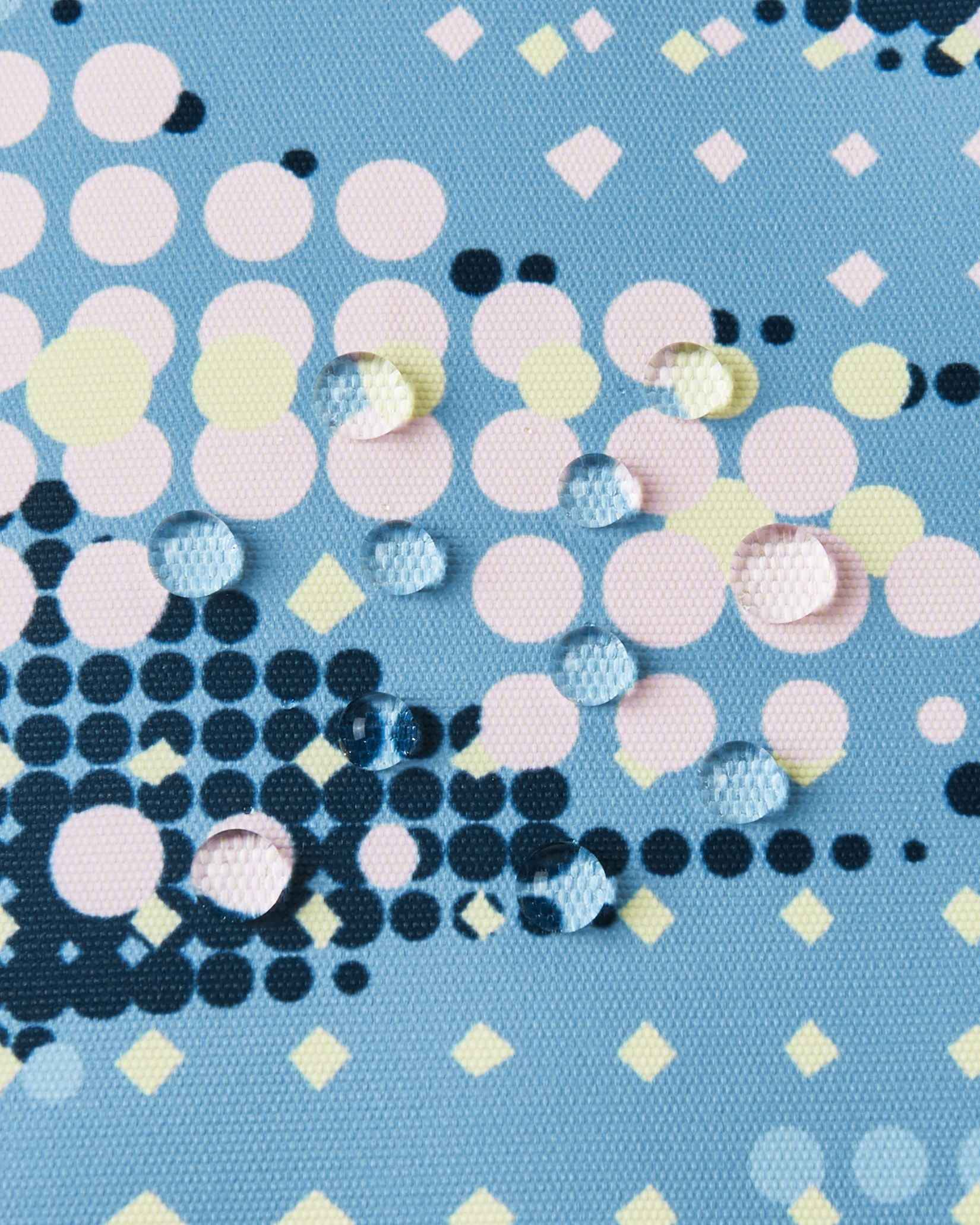 Macro close-up of water droplets perfectly beading on the surface of the frozen blue Reima Posio kids' ski jacket, demonstrating the high-performance waterproof and breathable Reimatec outer fabric.