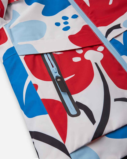 Close-up of the sealed, water-resistant zipper pocket on the front panel of the white Reima Posio kids' winter ski jacket, showcasing the durable construction and bright floral design.