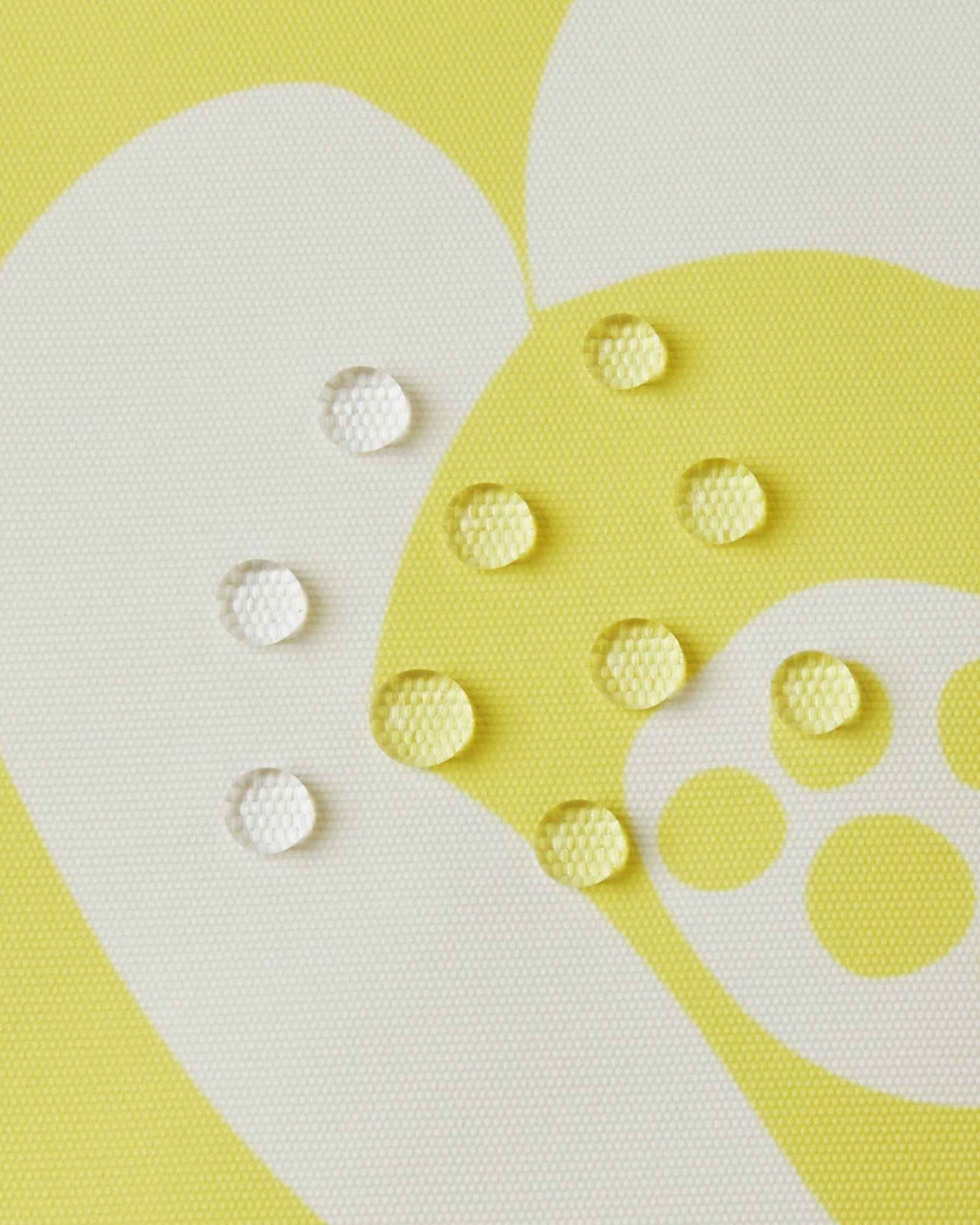 Macro close-up of water droplets perfectly beading on the surface of the yellow Reima Posio kids' ski jacket, demonstrating the high-performance waterproof and breathable Reimatec outer fabric.