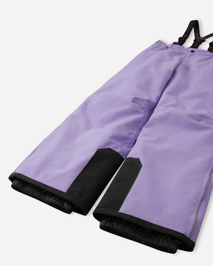 Detail view of the lower legs on the blooming lilac Reima Proxima kids' ski pants, emphasizing the rugged black reinforced hems to protect against ski edges and the inner elastic snow locks designed to securely grip boots and keep powder out.