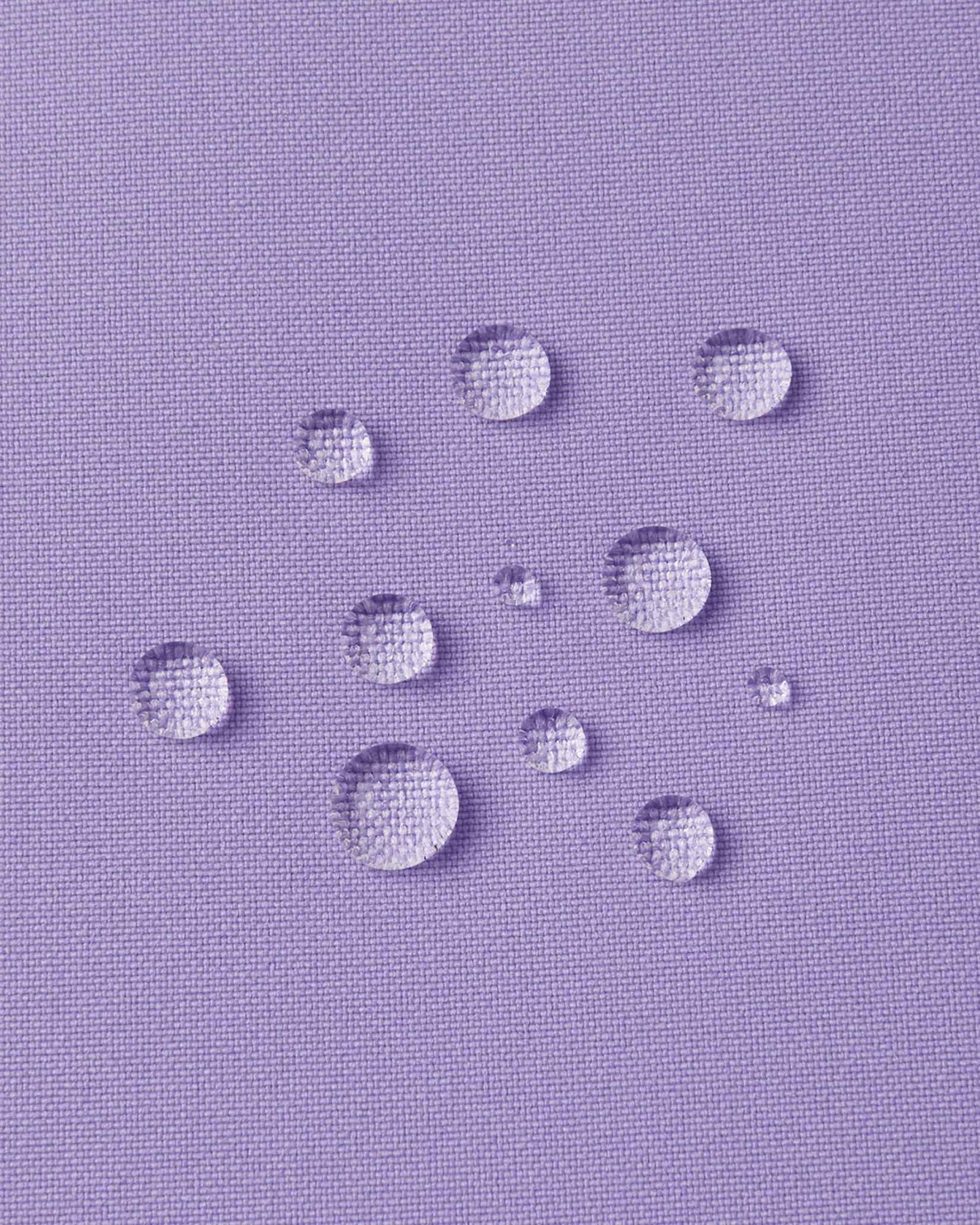 Macro close-up of water droplets actively beading and rolling off the blooming lilac outer shell of the Reima Proxima kids' ski pants, visually highlighting the high-performance breathable and waterproof Reimatec technology.