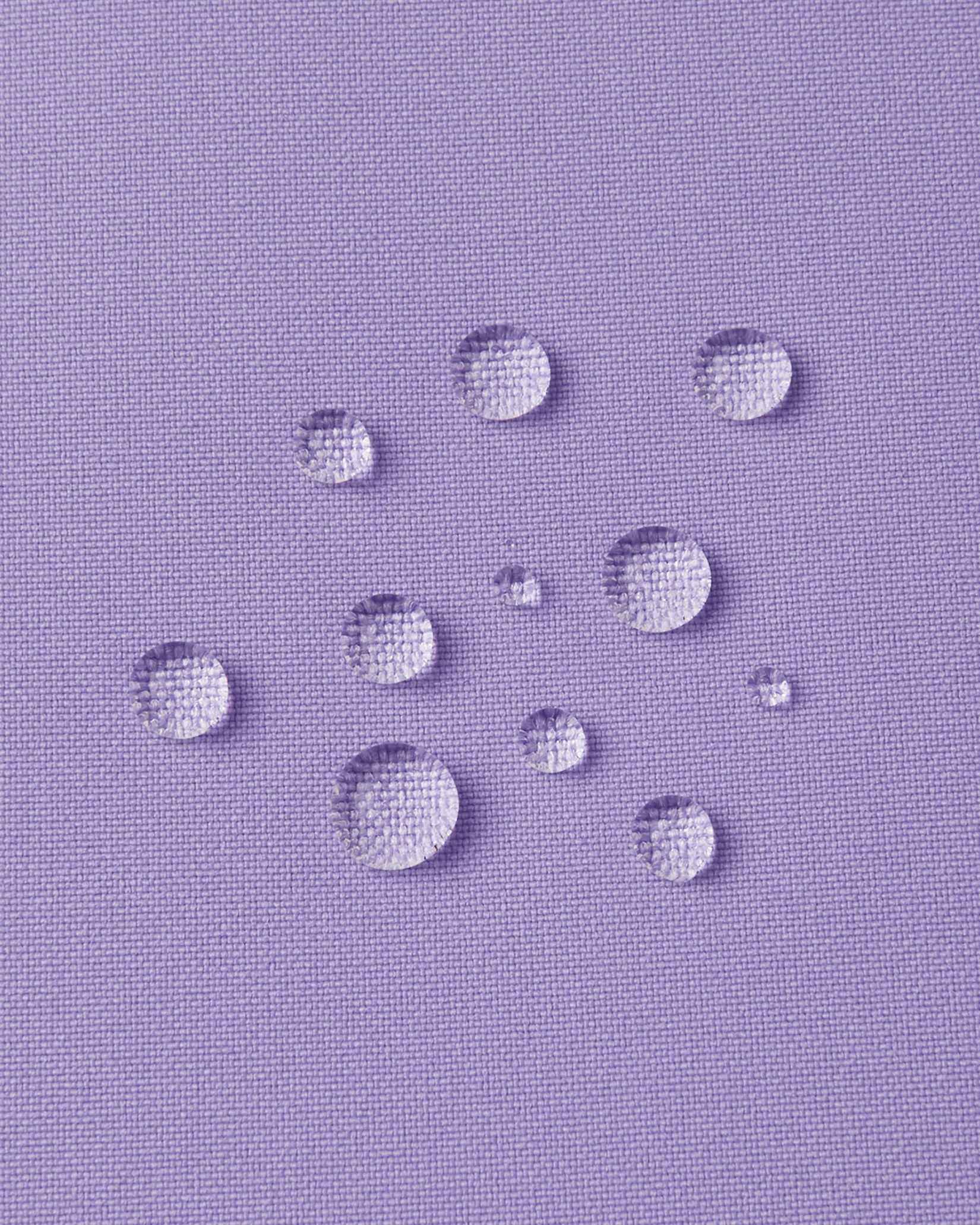 Macro close-up of water droplets actively beading and rolling off the blooming lilac outer shell of the Reima Proxima kids' ski pants, visually highlighting the high-performance breathable and waterproof Reimatec technology.
