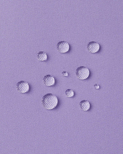 Macro close-up of water droplets actively beading and rolling off the blooming lilac outer shell of the Reima Proxima kids' ski pants, visually highlighting the high-performance breathable and waterproof Reimatec technology.