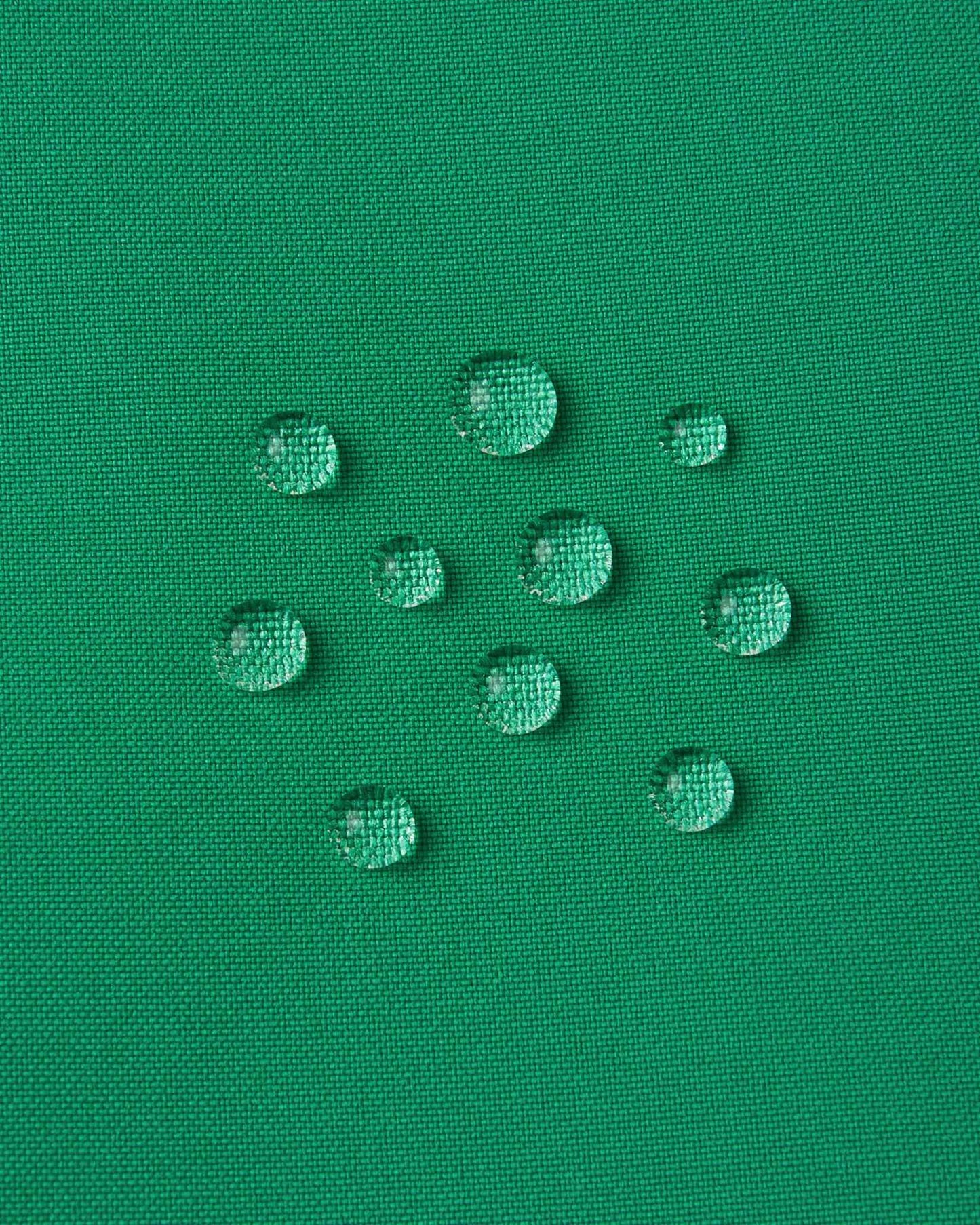 Macro close-up of water droplets actively beading and rolling off the bright green outer shell of the Reima Proxima kids' ski pants, visually highlighting the high-performance breathable and waterproof Reimatec technology.