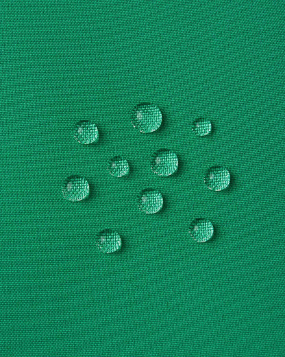 Macro close-up of water droplets actively beading and rolling off the bright green outer shell of the Reima Proxima kids' ski pants, visually highlighting the high-performance breathable and waterproof Reimatec technology.